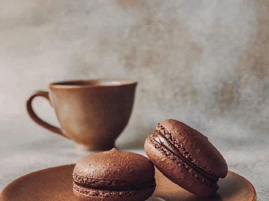 Tasse à café marron avec des macarons au chocolat